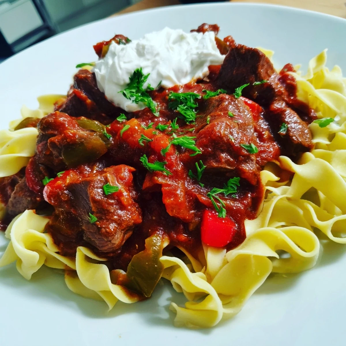 Fork-tender beef in savory stew, served over buttered noodles, showcasing the delicious Hungarian Goulash.