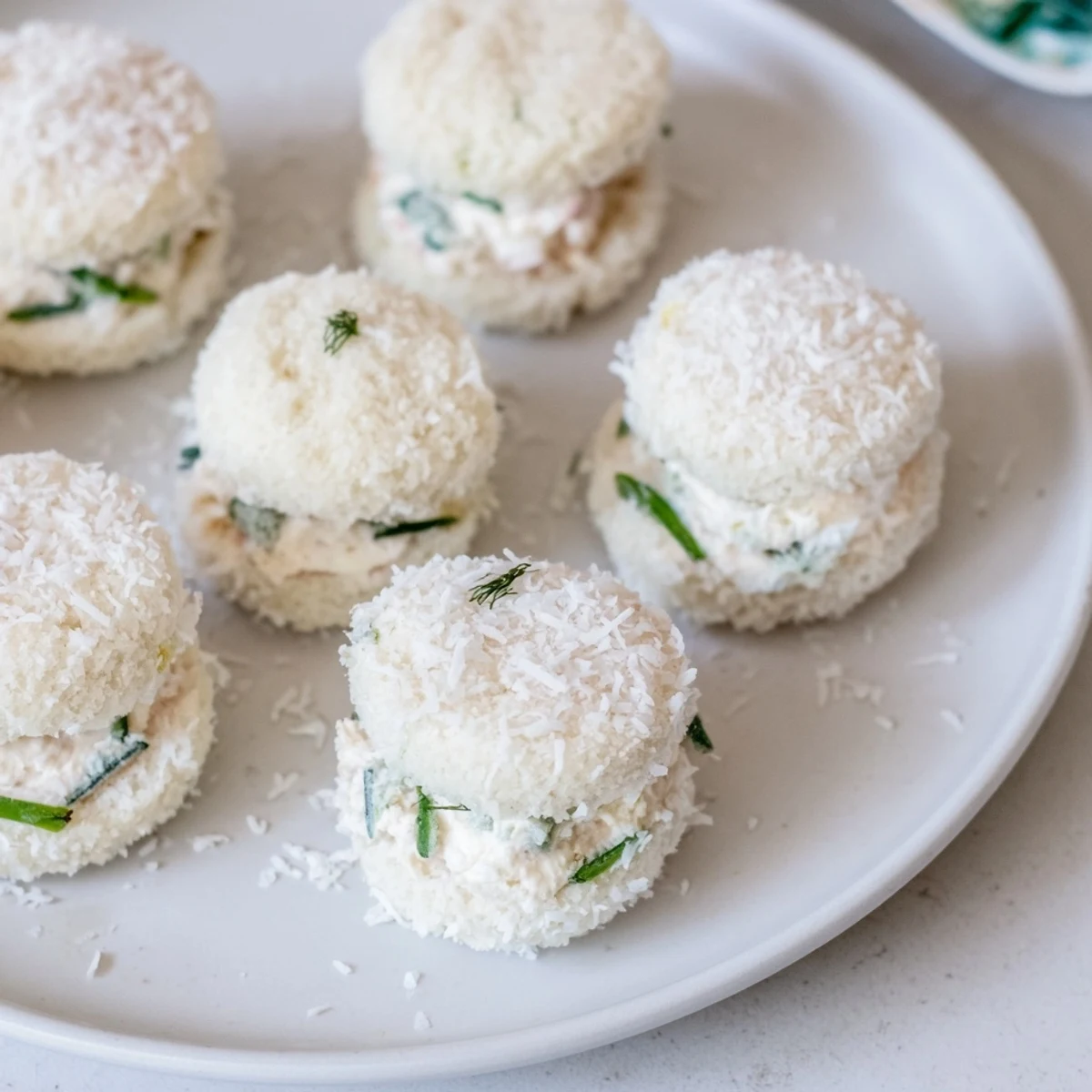 Snowball Tea Sandwich Bites, delicate, bite-sized, rolled in coconut for a festive appetizer presentation.