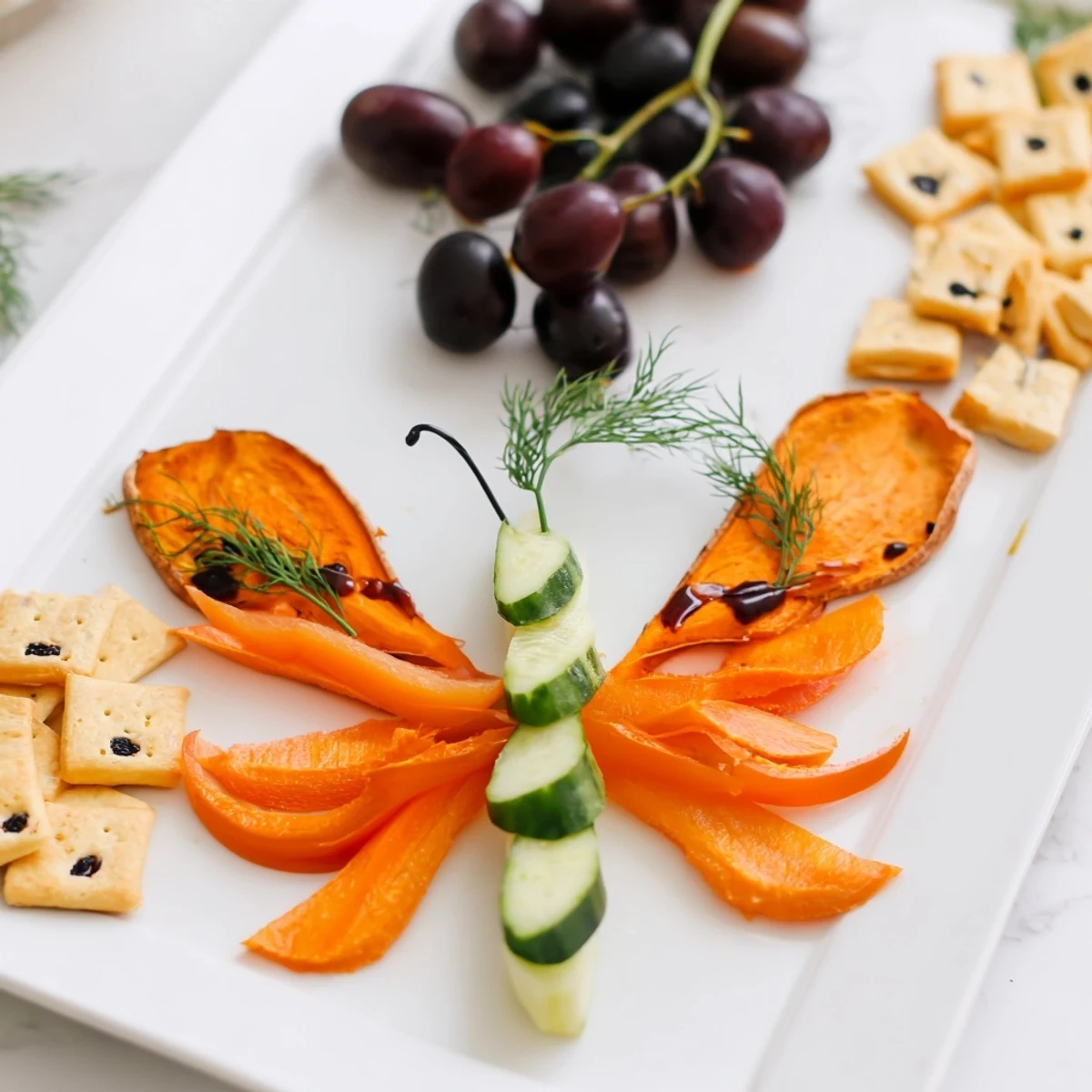 Arranged Monarch Butterfly Wings appetizer with sweet potatoes, olives, and a balsamic glaze drizzle ready to serve.