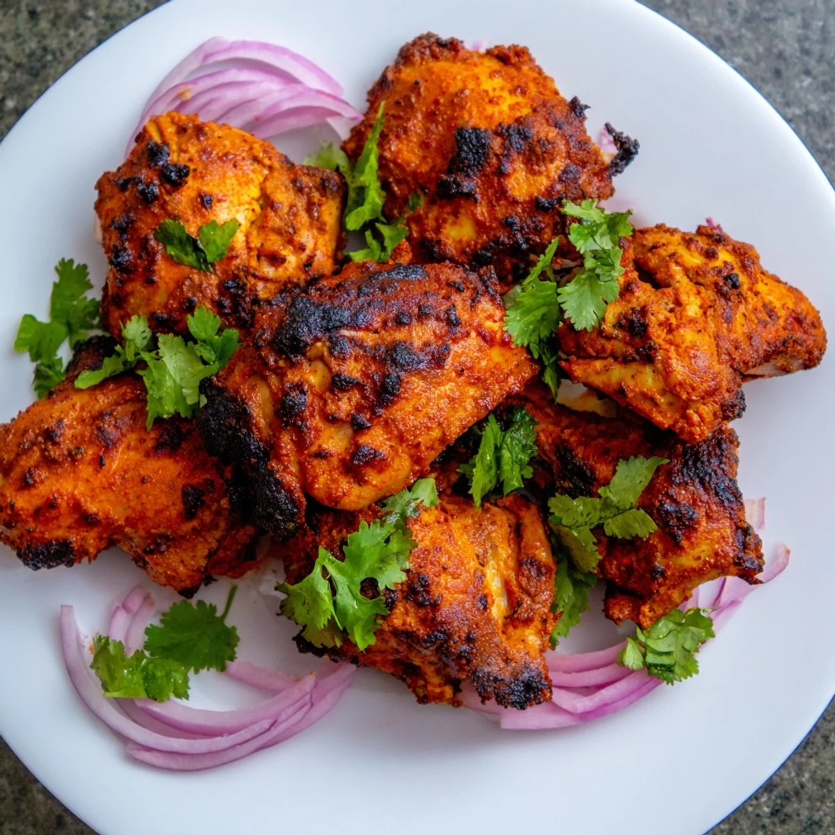 Aromatic Indian Tikka Spiced Chicken marinated in yogurt and spices, ready to be enjoyed with sliced red onions and a squeeze of lemon.