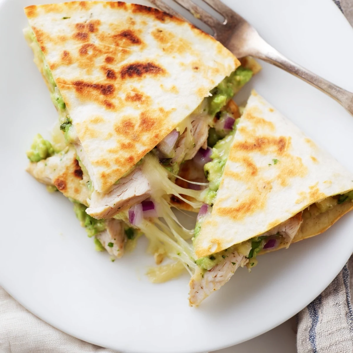 Close-up of a crispy Chicken Avocado Quesadilla revealing juicy chicken, creamy avocado mash, and melted cheese.