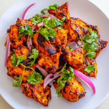 Vibrant Indian Tikka Spiced Chicken thighs with a crispy char, served hot alongside fluffy basmati rice and warm naan bread.  