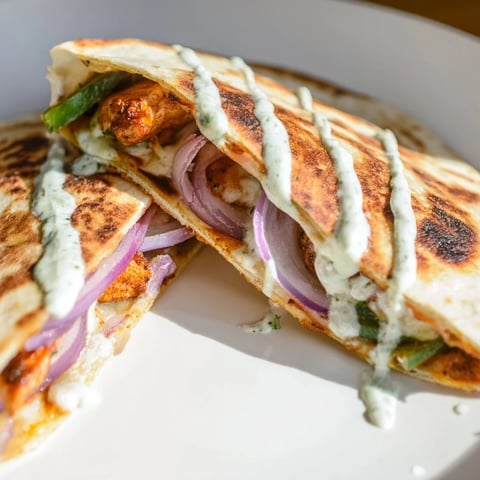 Golden-brown Tandoori Chicken Quesadilla, filled with melted cheese and tender, spiced chicken.
