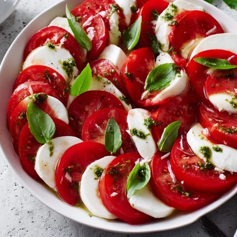 Close-up of a vibrant Caprese salad drizzled with basil vinaigrette, ready to be enjoyed.
