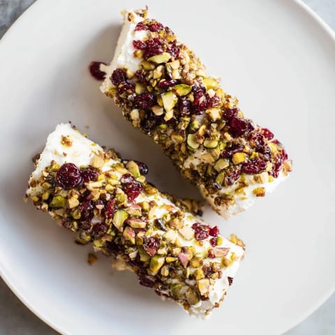 A close-up of festive Cranberry Goat Cheese Logs, showcasing the creamy cheese and colorful topping combination.