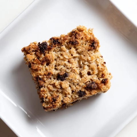 A square of Baked Oats That Taste Like Cake, fluffy and moist, hinting of banana and chocolate chips inside.