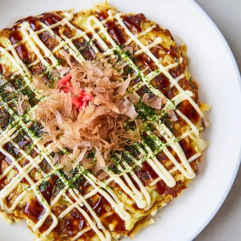 Golden Japanese okonomiyaki pancakes topped with creamy mayo, tangy sauce, and pickled ginger.  