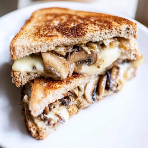 A close-up view shows the Mushroom Swiss Grilled Cheese resting on a wooden board, perfect alongside a steaming bowl of tomato soup.