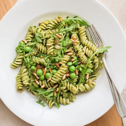 Vibrant Spring Green Pesto Pasta Salad tossed with basil pesto, bright green peas, and arugula for a refreshing lunch.  