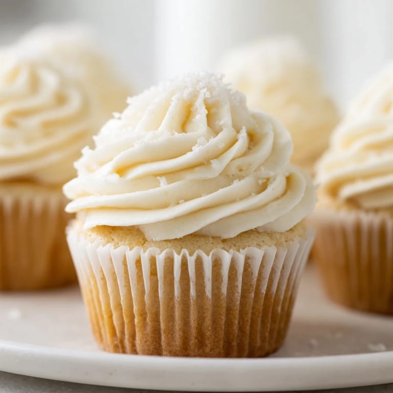 Homemade vanilla cupcakes: a close-up shows tender cake beneath sweet buttercream swirls.