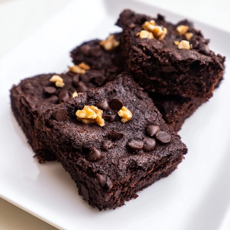 Perfectly square black bean brownies, with a moist interior and a sprinkle of dark chocolate, ready to serve.