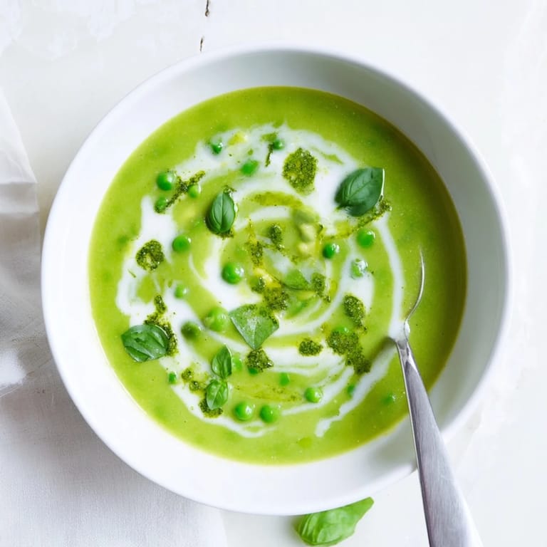 Creamy green Courgette, Pea and Pesto Soup served in a rustic white bowl with a drizzle of olive oil.