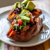 Golden roasted sweet potatoes split open, topped with smoky chipotle black beans and fresh tomato salsa.  