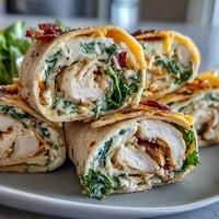 Turkey, cheese, and spinach tortilla pinwheels with creamy filling and fresh greens, perfect for quick snacks or party platters.